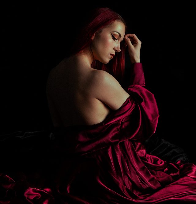 Een vrouw in een satijnen kamerjas ontbloot haar schouder